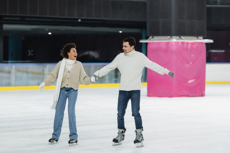 Excited african american woman ice skating with boyfriend on rinkの写真素材