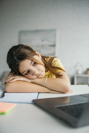 tired girl lying on table near notebook and laptop with blank screen at homeの写真素材