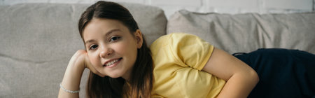 joyful girl relaxing on couch at home and smiling at camera, bannerの写真素材