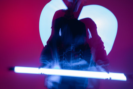 motion blur of woman posing with vibrant neon lamps on purple backgroundの写真素材
