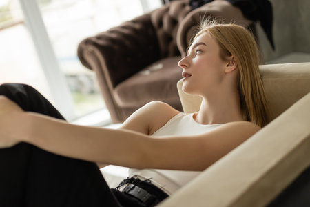 Young woman in jeans and top resting on sofa at home