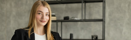 pretty blonde woman with natural makeup smiling at camera in blurred apartment, bannerの写真素材