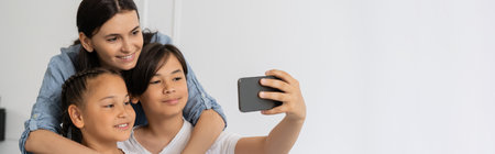 Asian boy taking selfie with sister and mom at home, bannerの写真素材