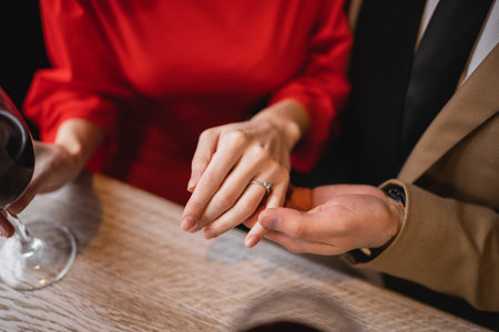 cropped view of man holding hand of woman with engagement ring on finger on valentines day