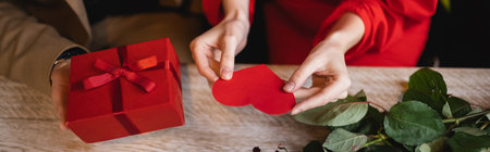 top view of cropped man holding present near girlfriend with red heart-shaped greeting card on valentines day, bannerの写真素材