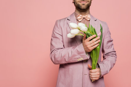 Cropped view of bearded host of event holding tulips isolated on pinkの写真素材