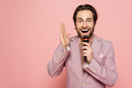 Amazed host of event taking at microphone isolated on pink