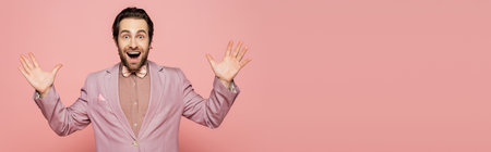 Excited host of event in jacket and bow tie looking at camera on pink background, bannerの写真素材
