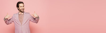 Positive host of event pointing with fingers and looking at camera on pink background, bannerの写真素材