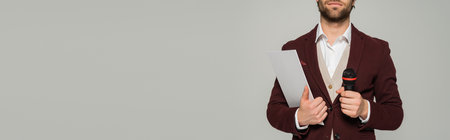 cropped view of bearded host of event in formal wear holding microphone and clipboard isolated on...