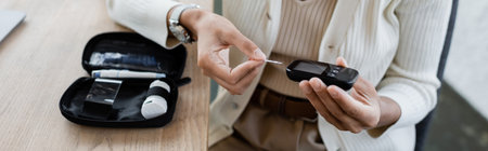 Cropped view of african american businesswoman holding glucometer near diabetes kit in office, bannerの写真素材