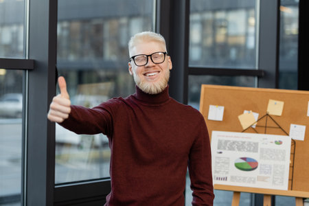bearded albino businessman in glasses smiling and showing thumb up in office
