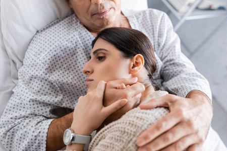 Top view of sick elderly patient hugging daughter in clinicの写真素材