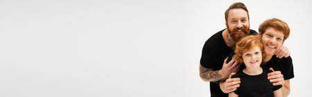 family portrait of redhead boy with father and tattooed grandpa embracing isolated on grey, bannerの写真素材