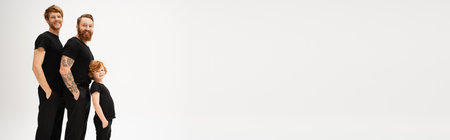 redhead men and boy in black t-shirts and trousers standing with hands in pockets isolated on grey, bannerの写真素材