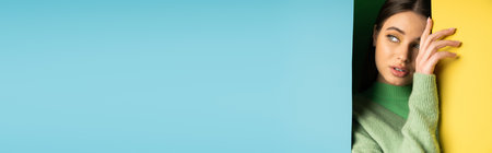 Pretty teen girl in jumper looking away while touching colorful background, bannerの写真素材