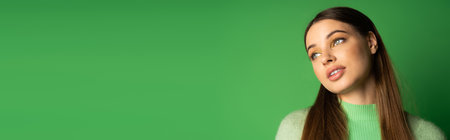 Young brunette teenager looking away on green background with copy space, bannerの写真素材