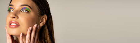 Pretty teen girl with creative visage touching face isolated on grey, bannerの写真素材