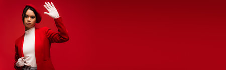 Trendy asian woman in jacket waving hand at camera isolated on red, bannerの写真素材