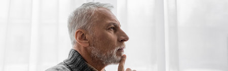 profile of senior grey haired man with alzheimer disease touching chin while thinking at home, bannerの写真素材