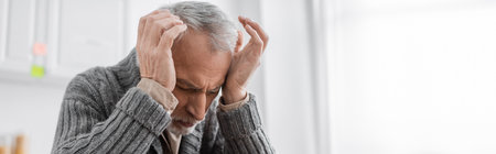 senior man suffering from azheimers disease and headache while holding hands near head, bannerの写真素材