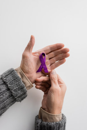 top view of cropped senior man with alzheimer disease holding purple awareness ribbon on white backgroundの写真素材