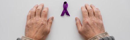top view of cropped male hands near purple alzheimer disease awareness ribbon on white surface, bannerの写真素材