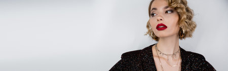 young woman with blonde curly hair and red lips posing on grey background, banner
