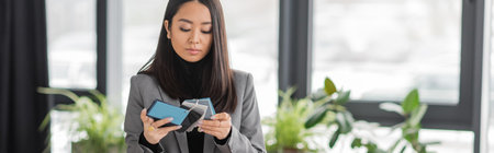 Brunette asian interior designer looking at color samples in studio, bannerの写真素材