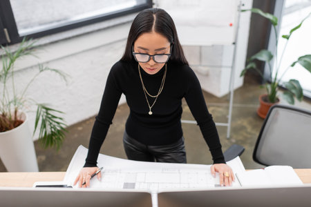 Young asian interior designer working with computers and blueprint in studio