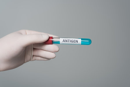 Cropped view of doctor in latex glove holding test tube with antigen lettering isolated on greyの写真素材