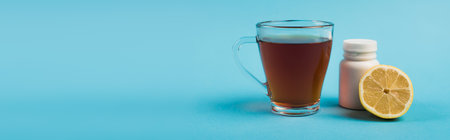 Cup of tea near jar with pills and lemon on blue background, banner