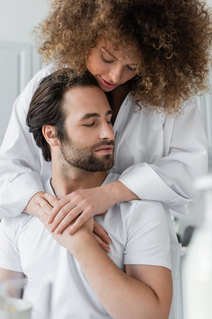 sensual young woman hugging bearded boyfriend in kitchen