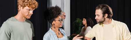 happy african american woman talking to bearded actor near interracial students in theater studio,...