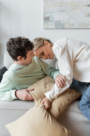 happy young couple laughing while having pillow fight in living room