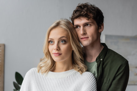 portrait of curly young man and blonde woman in white sweaterの写真素材
