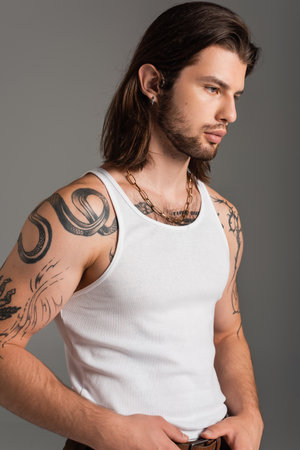 Long haired man with tattoo on body posing isolated on greyの写真素材