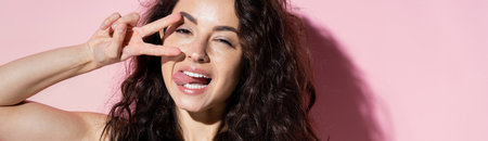 Freckled woman showing peace sign on pink background, bannerの写真素材