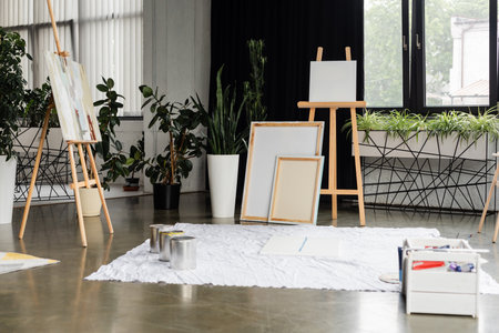 Jars with paints on cloth near canvases in studio