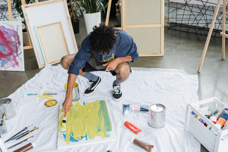 African american artist painting on canvas on cloth in art studio