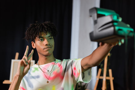 African american artist taking selfie on vintage camera in studio
