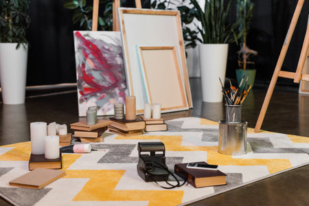 Vintage camera and books near blurred canvases in art studio