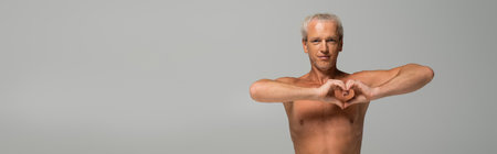 shirtless man showing heart sign isolated on grey, bannerの写真素材