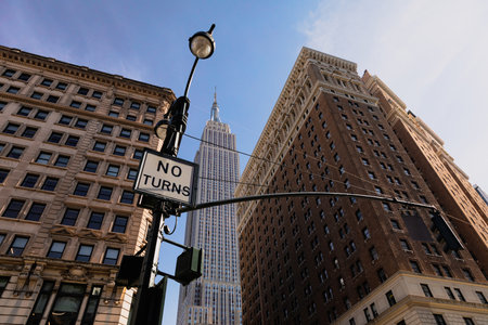 low angle view of lantern with no turns sign near high-rise houses and Empire State building in...