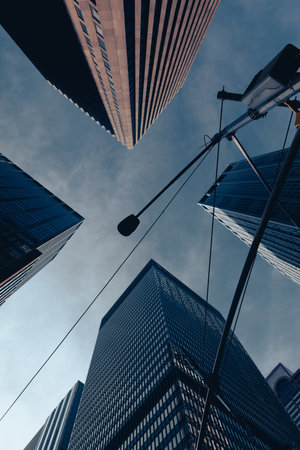 bottom view of street lamp near skyscrapers against blue and cloudy sky in New York City