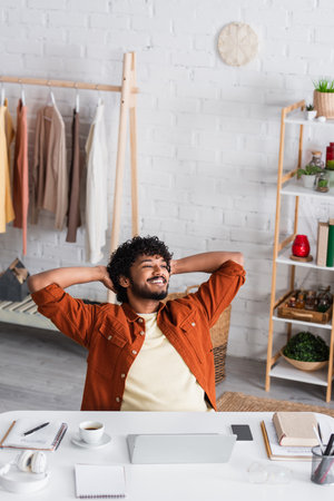 Positive indian copywriter sitting near working table at homeの写真素材
