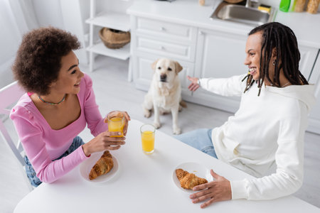 High angle view of african american couple talking near breakfast and blurred labrador at homeの写真素材