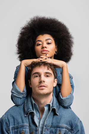 brunette african american woman looking at camera with stylish man isolated on greyの写真素材