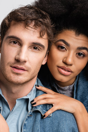 portrait of curly african american woman and good looking man looking at camera isolated on greyの写真素材