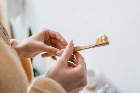 cropped view of young woman holding toothbrush with toothpaste